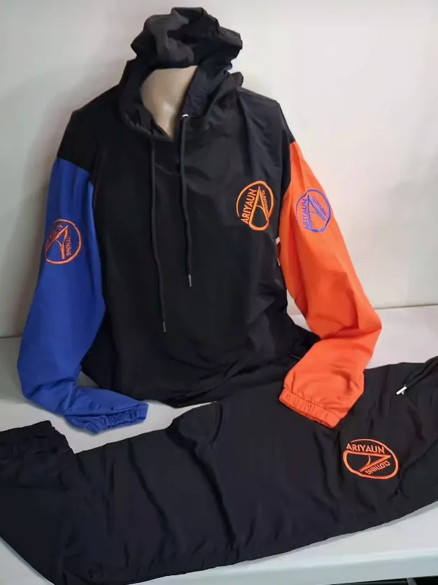 Black tracksuit with one royal blue and one orange sleeve and orange Ariyaun circle logos, on a mannequin